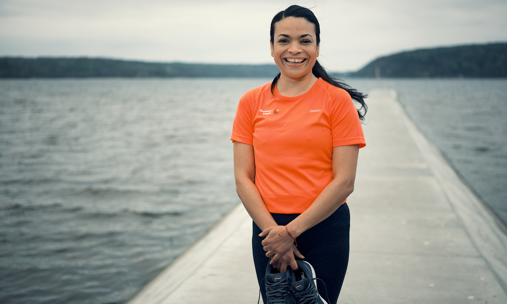 En kvinna med orange t-shirt står vid en sjö