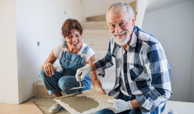 Old man and woman working on interior of new house or flat.
