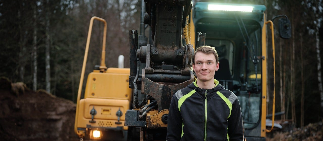 En ung man framför sin grävmaskin