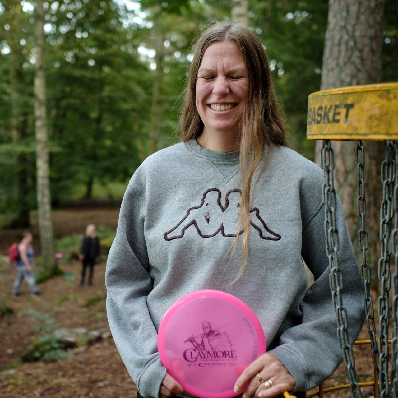 Leende kvinna bredvid en discgolfkorg