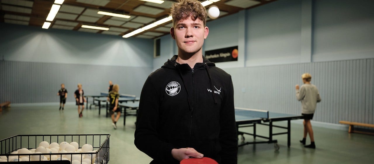 En ung man framför pingisbord