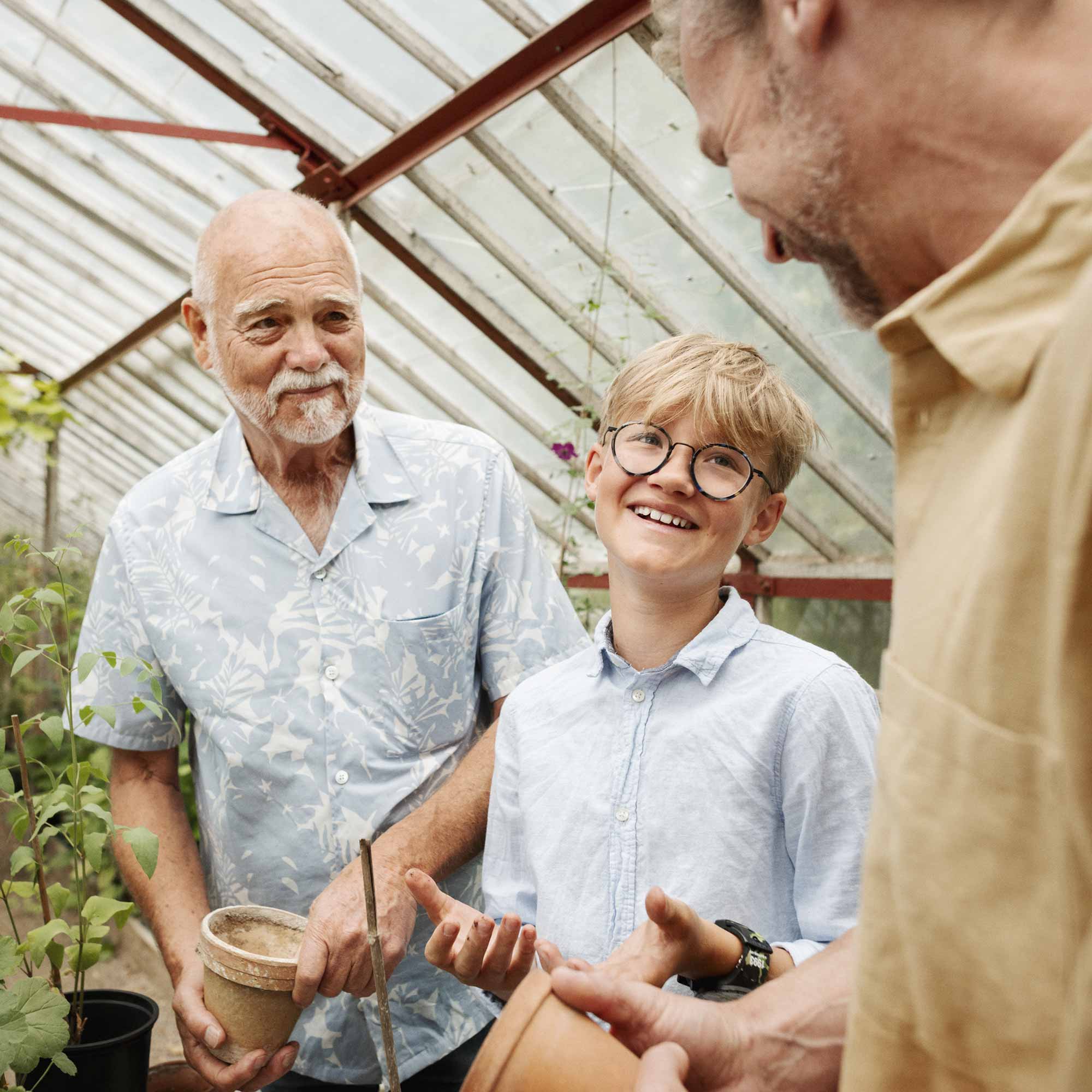 Morfar, pappa och barn jobbar och pratar i växthuset