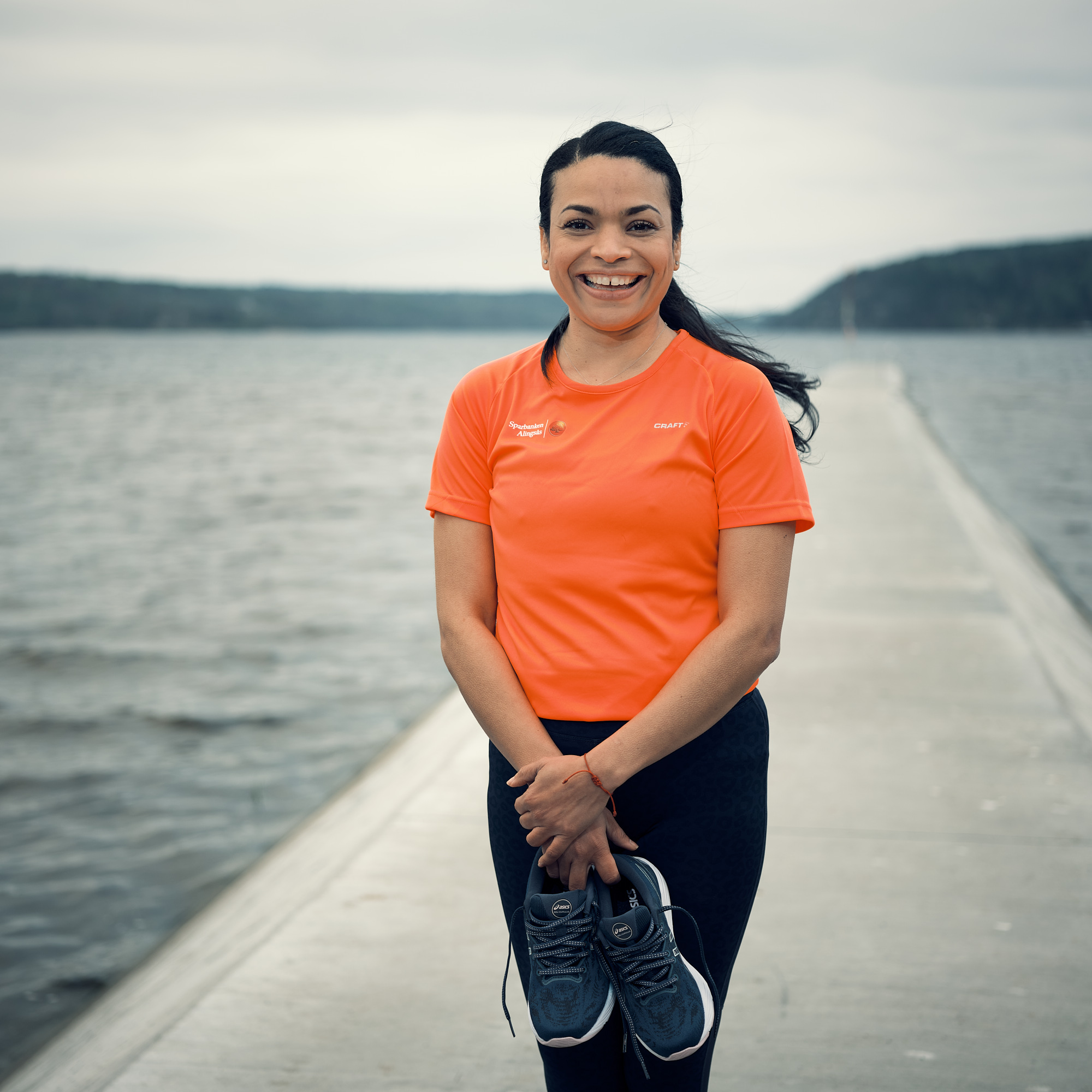 En kvinna med orange t-shirt står vid en sjö