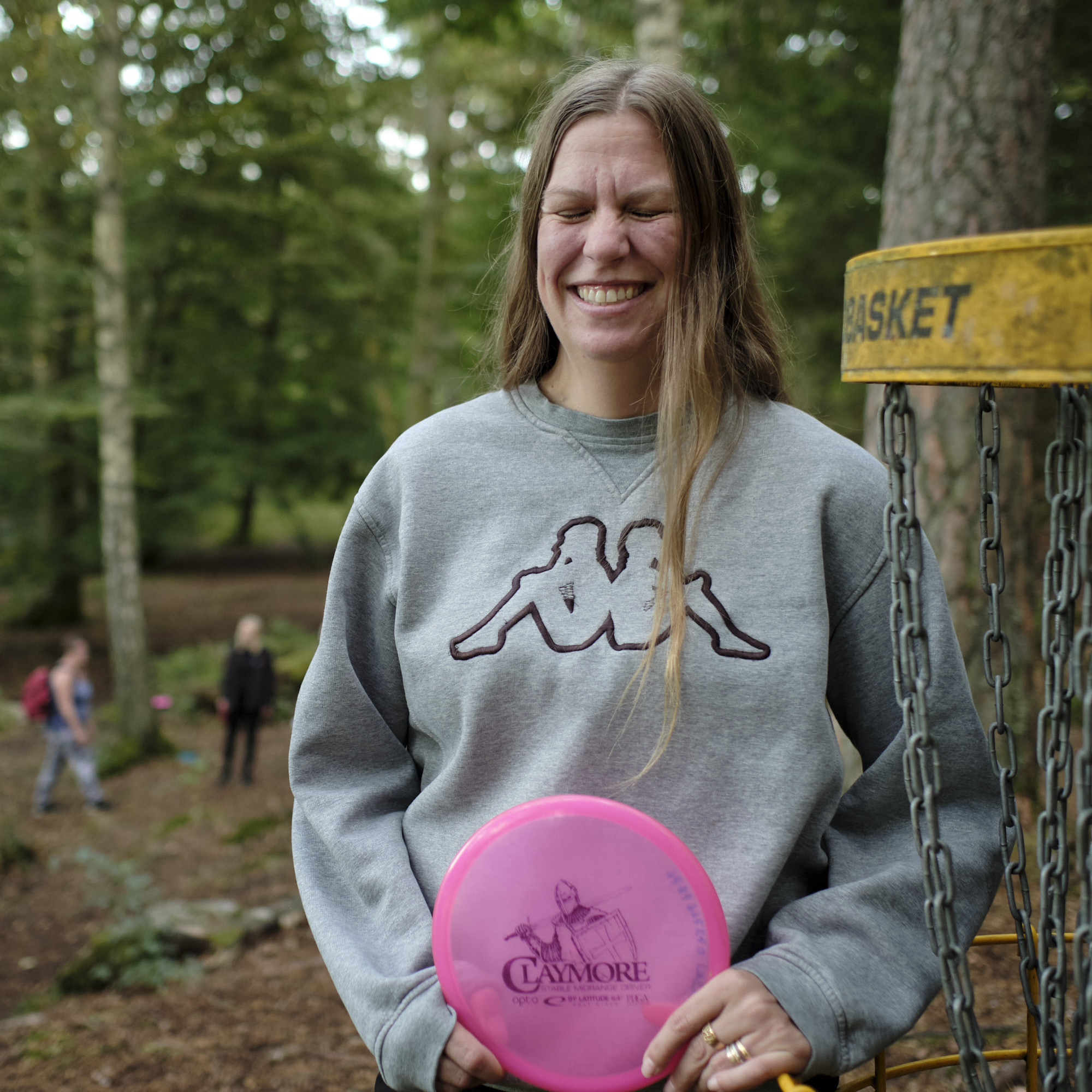 Leende kvinna bredvid en discgolfkorg