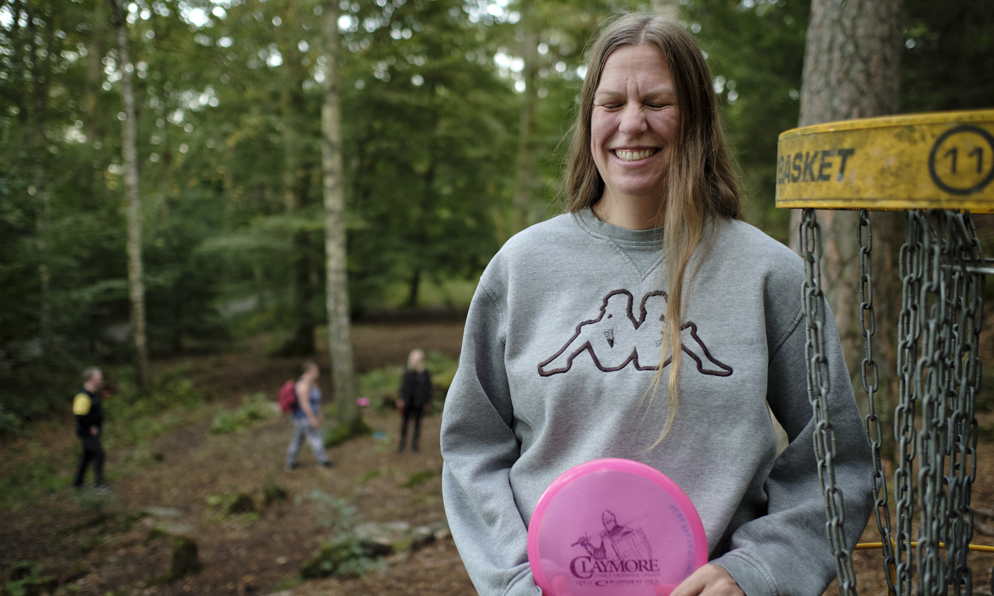 Leende kvinna bredvid en discgolfkorg