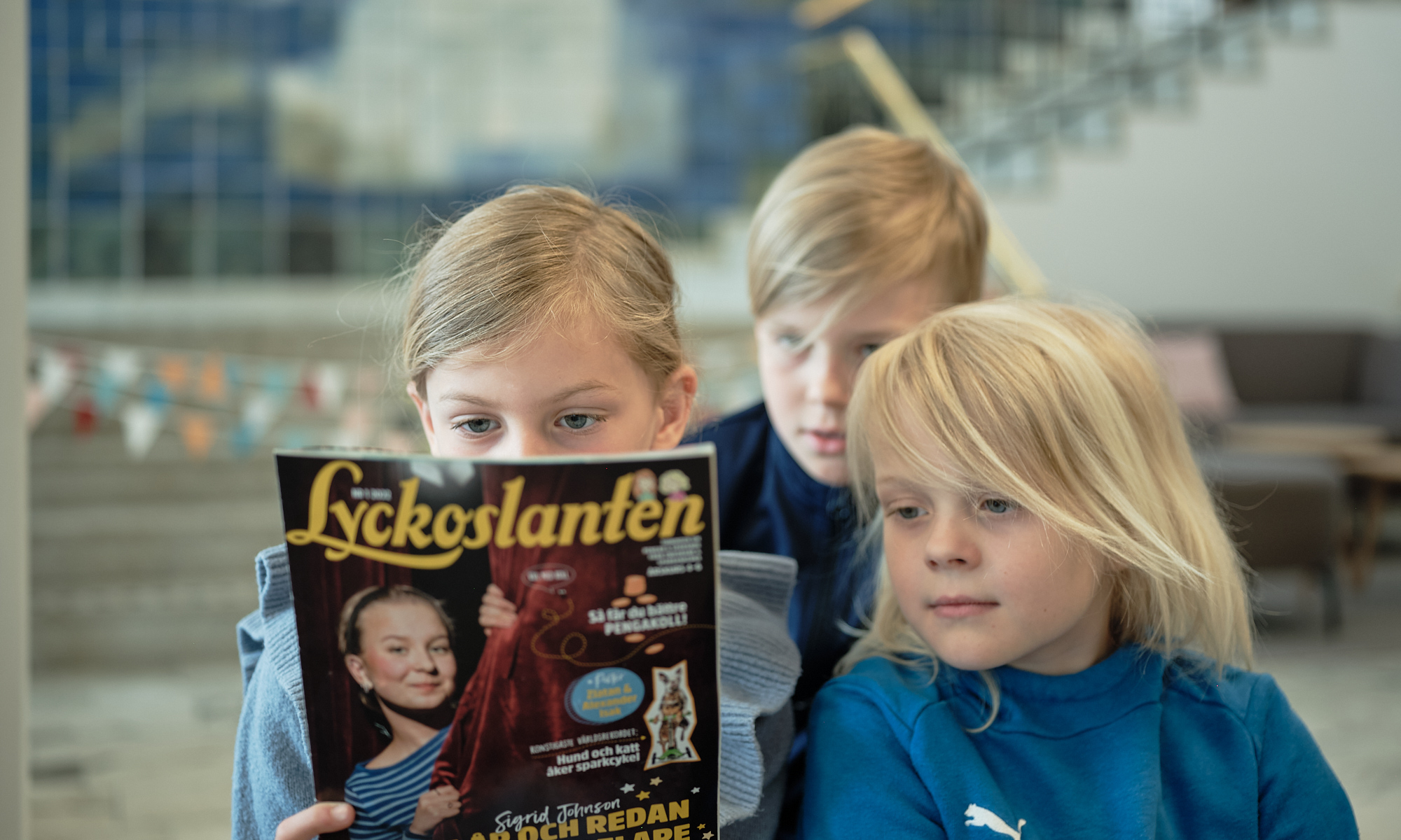 tre barn läser baksidan av en tidning 