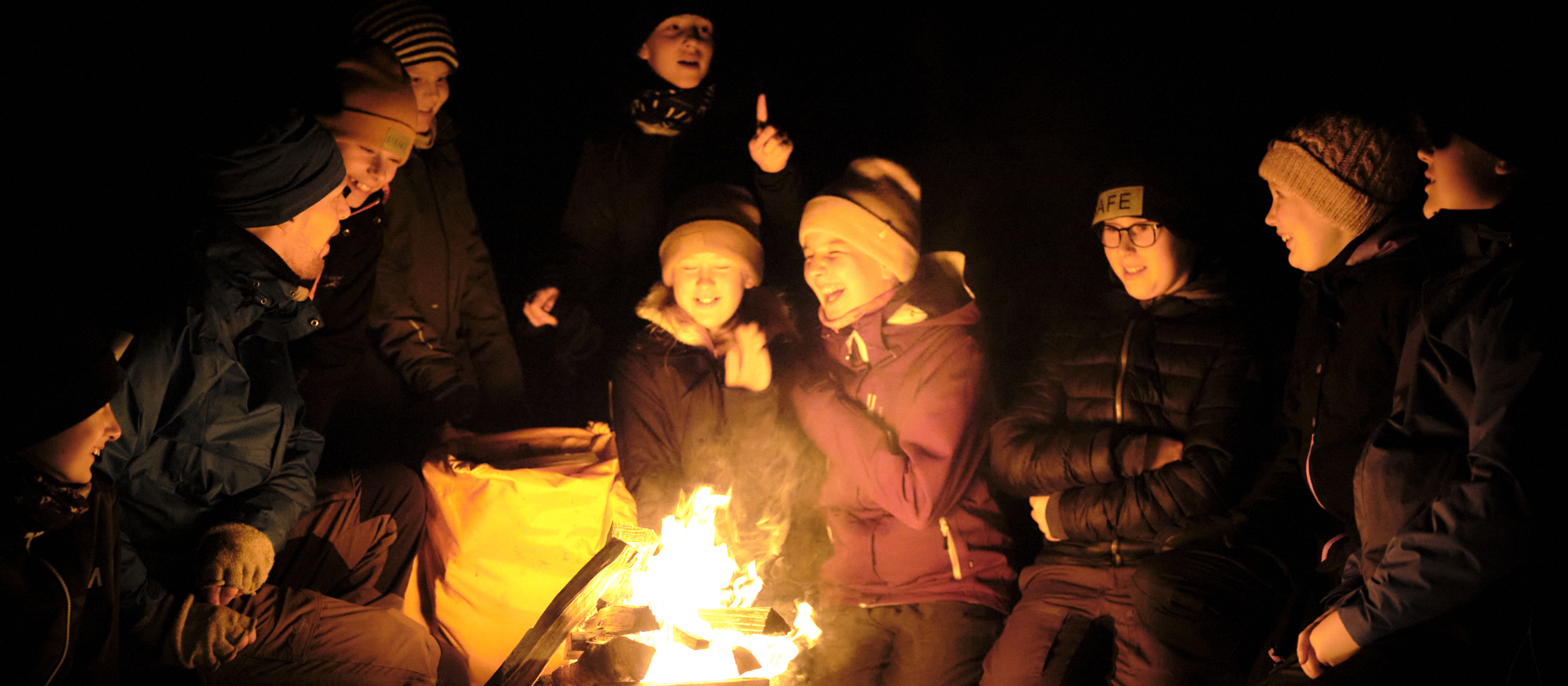 En grupp barn som skrattar och sitter vid en eld