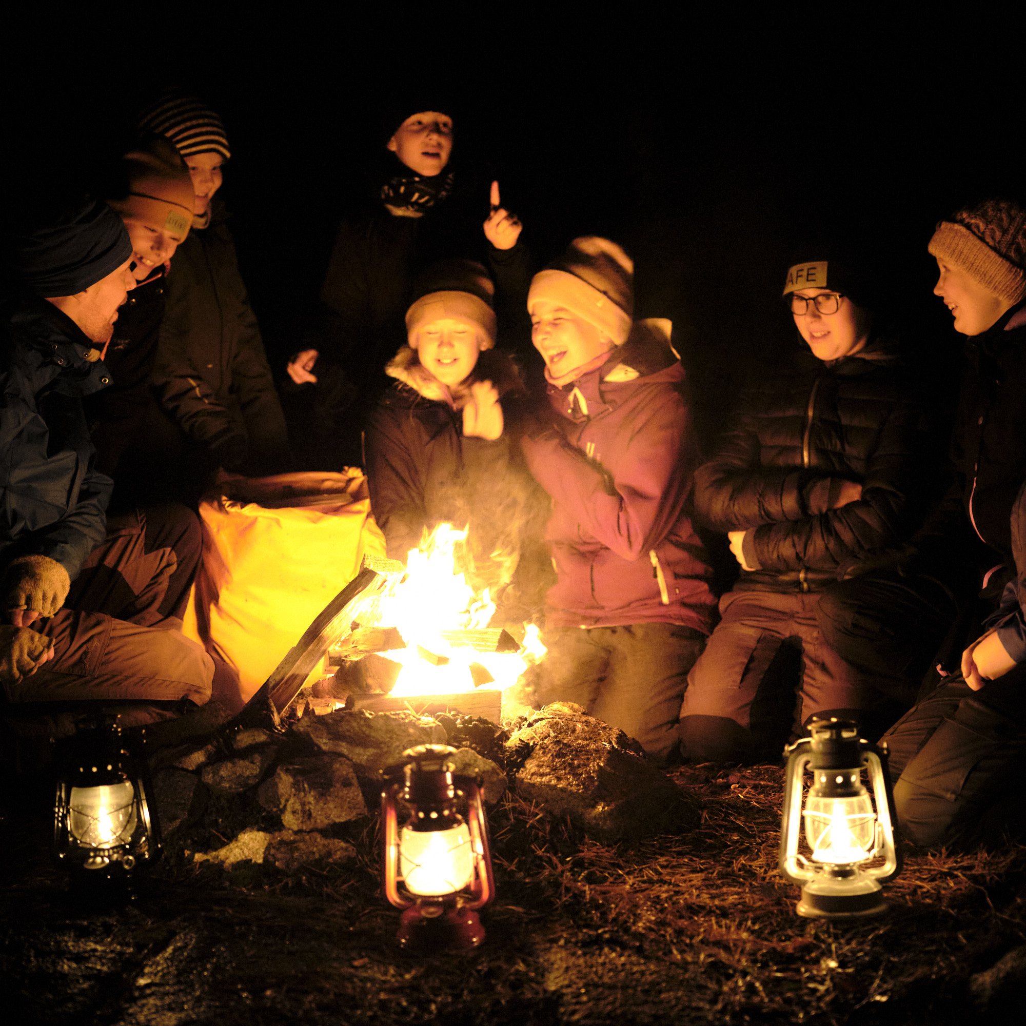 En grupp barn som skrattar och sitter vid en eld