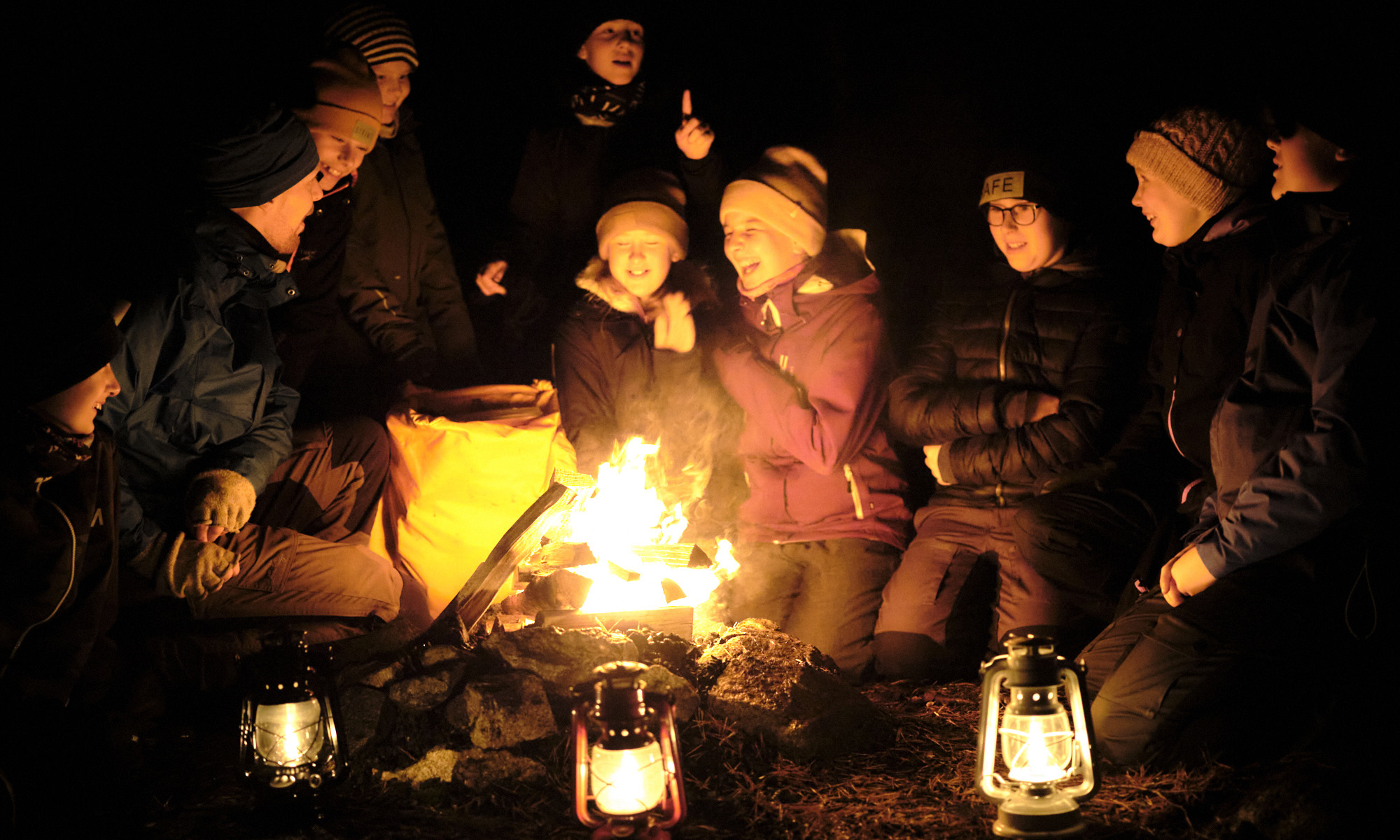 En grupp barn som skrattar och sitter vid en eld