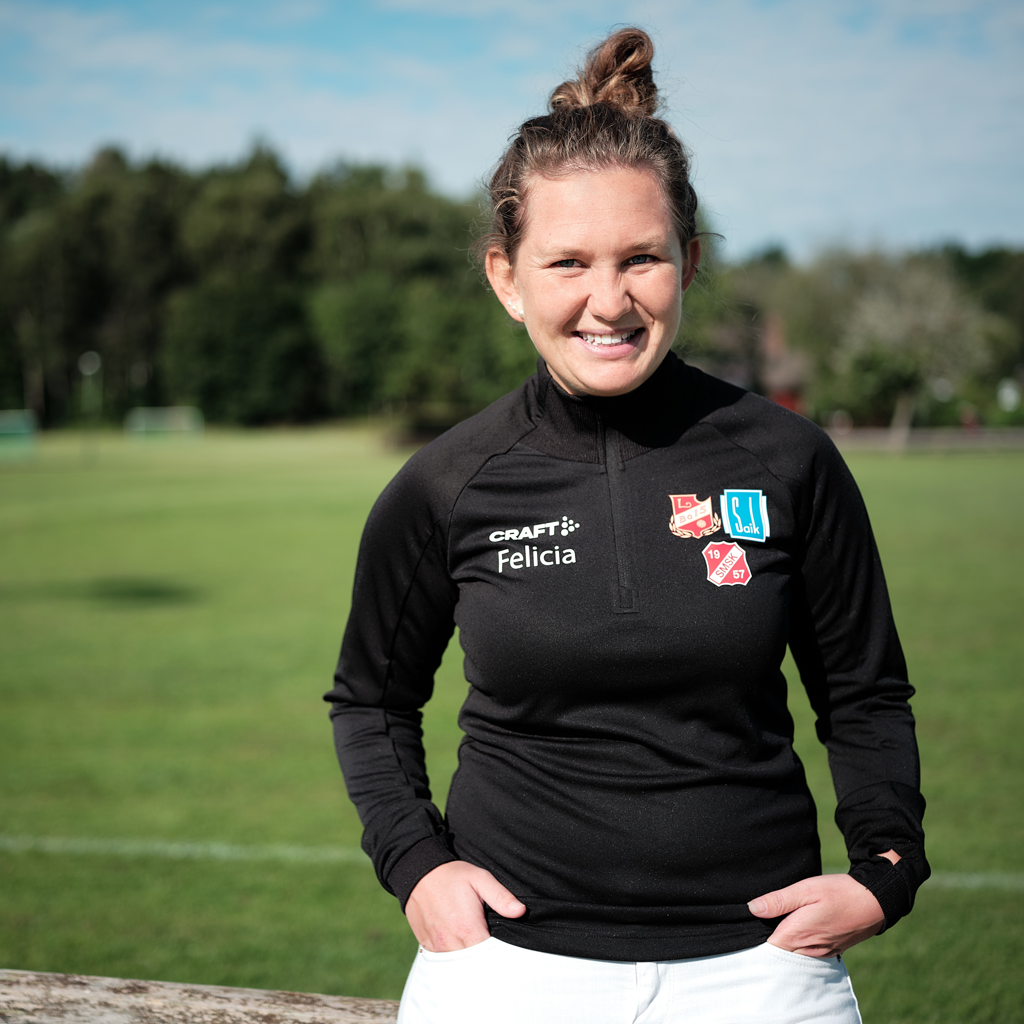 Leende kvinna bredvid en fotbollsplan