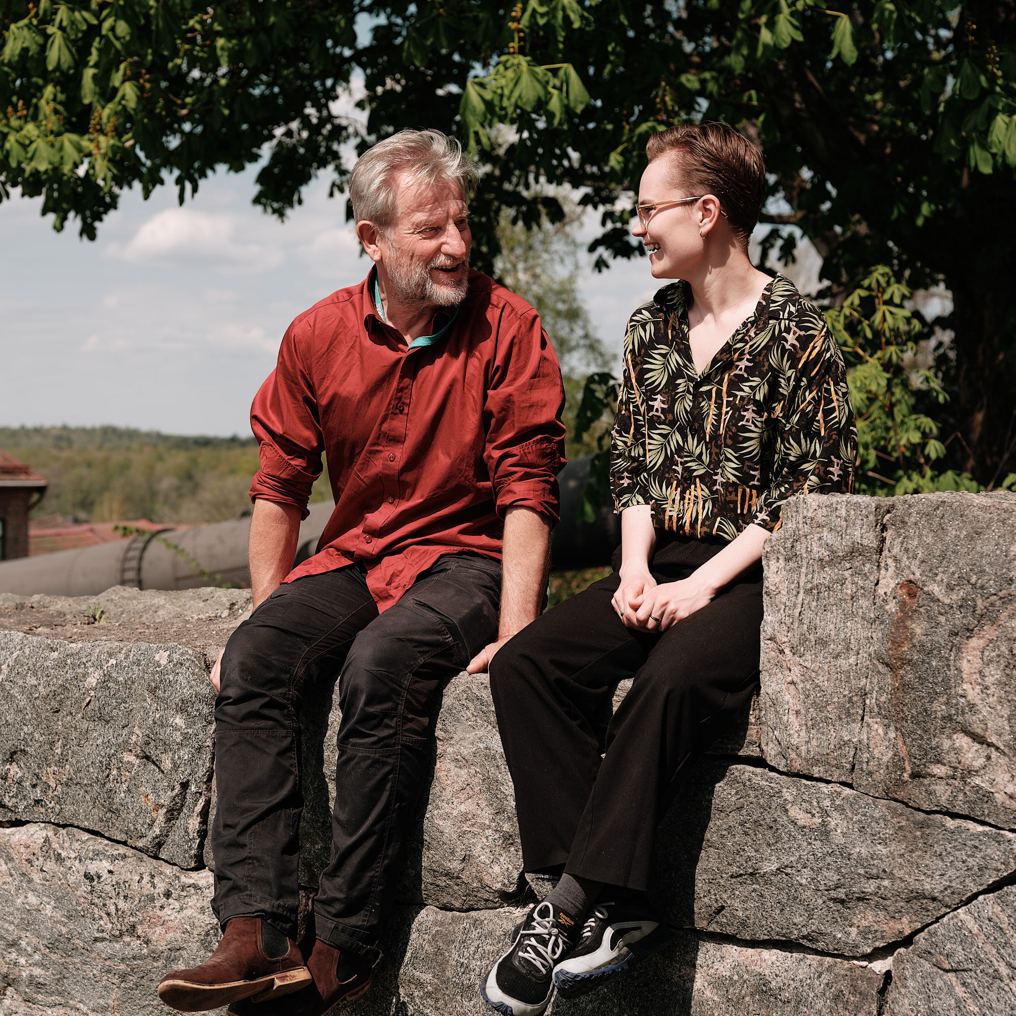 En man och en kvinna sitter på en stenmur 
